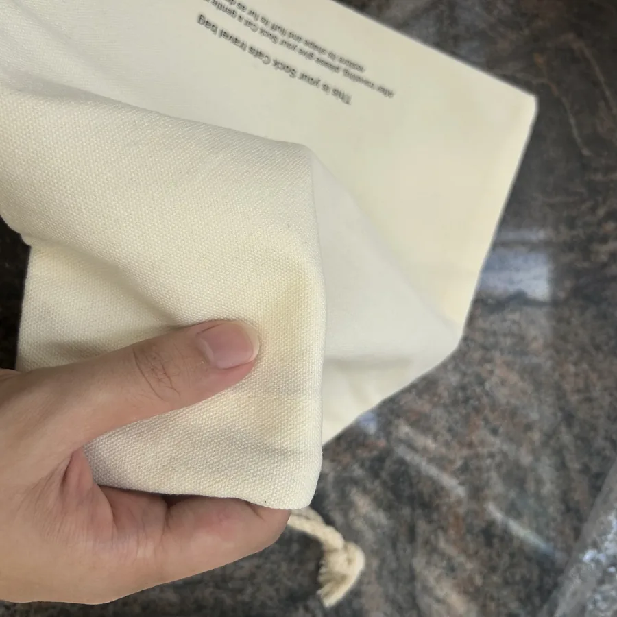 Close-up of natural cotton drawstring bag weave held by hand